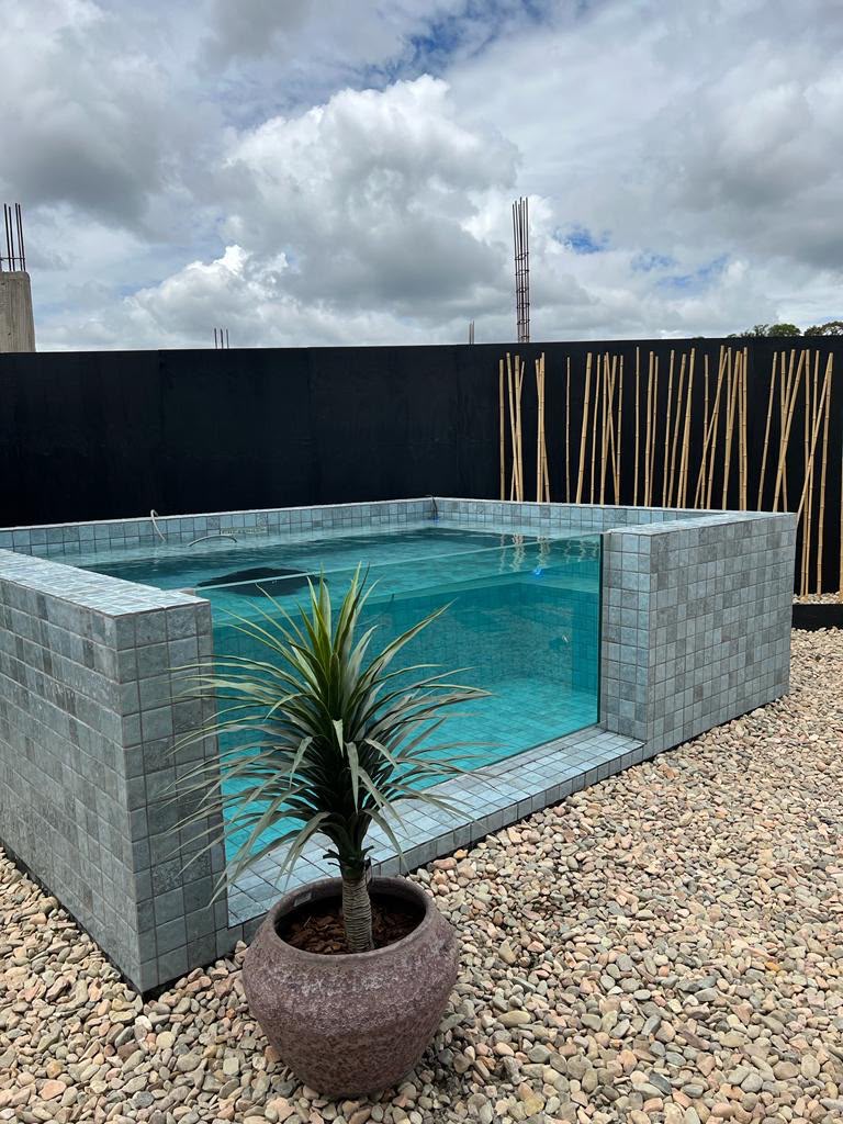 Piscina pastilhada elevada com parede de vidro