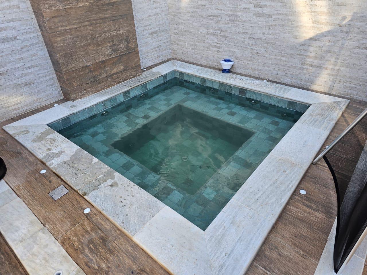 Piscina pastilhada verde com deck de madeira