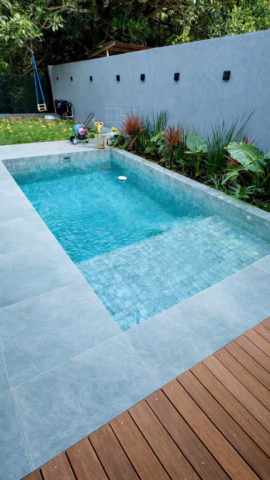Piscina pastilhada com deck e paisagismo